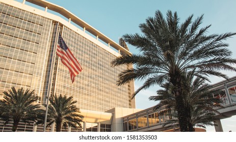 ORLANDO, FLORIDA - NOV 11, 2019: Advent Health Hospital Main Building At Sunset With An American Flag And Palm Trees.