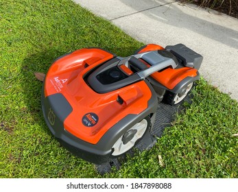 Orlando, FL./USA - 9/30/20:  A Husqvarna Autonomous Lawn Mower Mowing Near A Lake In The Laureate Park Neighborhood In Orlando, Florida