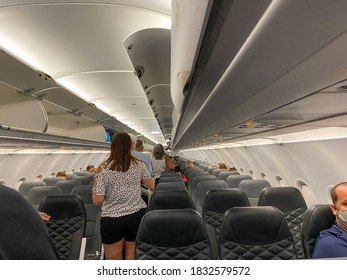 Orlando, FL/USA-10/2/20: People Walking Down The Aisle Boarding An Airplane While Wearing Masks And Social Distancing.