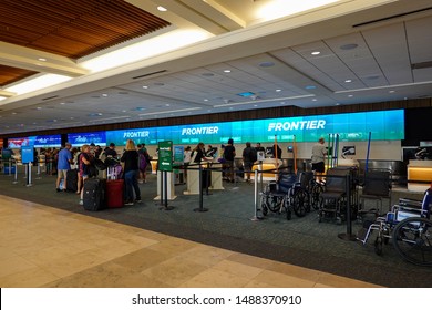 Orlando, FL/USA-8/22/19: People Waiting To Get Their Tickets At An Airline Checkin Counter At A Busy  Airport.