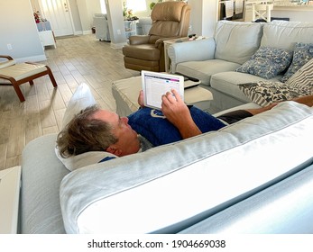 Orlando,FL USA - January 25, 2021:  A Senior Man Reading The News On His IPad While Laying On The Couch.