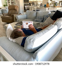 Orlando,FL USA - January 25, 2021:  A Senior Man Reading The News On His IPad While Laying On The Couch.