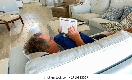 Orlando,FL USA - January 25, 2021:  A Senior Man Reading The News On His IPad While Laying On The Couch.