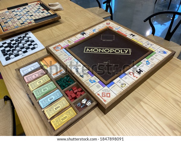 Orlando,FL/USA-10/20/20: A\
wooden  Monopoly game board, by Hasbro,  with the game pieces in a\
wooden drawer on a\
table.