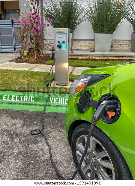 Orlando,FL/USA-12/14/19: A lime green electric\
vehicle charging at a free public charging\
station.