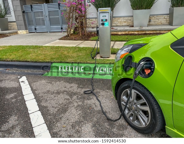 Orlando,FL/USA-12/14/19: A lime green electric\
vehicle charging at a free public charging\
station.
