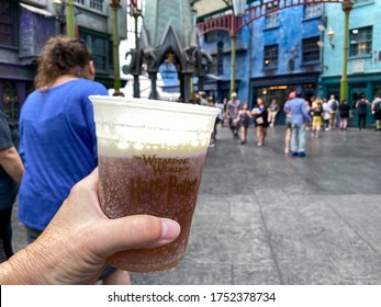 Orlando,FL/USA-2/16/20: A person's hand holding a plastic cup of butterbeer at Wizarding World of Harry Potter in the Universal Studios Resort theme park.
