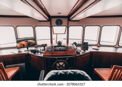 An orlop deck area inside of a deckhouse of a safari yacht or a boat with a control panel on the wooden base and many navigation devices: compass, radio transceiver, radars, surveillance, dashboards
