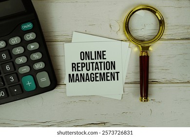 ORM (Online Reputation Management ) text message on sticky note with magnifying glass and calculator on wooden background