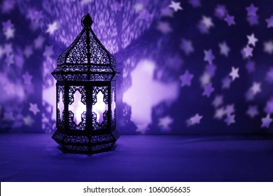 Ornamental Arabic lantern with burning candle glowing at night and glittering stars shaped bokeh lights. Festive greeting card, invitation for Muslim holy month Ramadan Kareem. Dark background. - Powered by Shutterstock