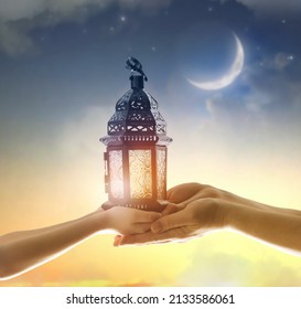 Ornamental Arabic lantern with burning candle glowing in hand. Festive greeting card, invitation for Muslim holy month Ramadan Kareem.