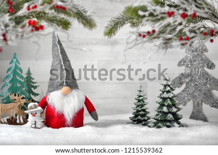 Ornamental arrangement for winter and Christmas, with a Santa puppet, snowman, reindeers and trees on snow