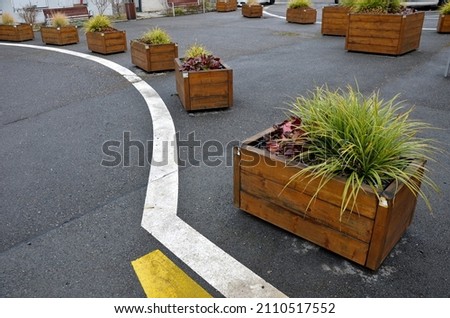 ornamental flower pots next to the road to the square. ornamental perennial flowers grass. block shape flower pot made of wood material. camping bench with table