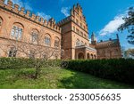 Ornate brick facade of the historic residence with blooming trees in the foreground. The architecture showcases Moorish-Byzantine style with arched windows and decorative battlements