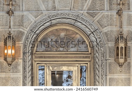 ornate building entrance detail with arched doorway and gold metallic lanterns (brick residential building in the style of urban theater in brooklyn new york) apartment complex condominium co-op