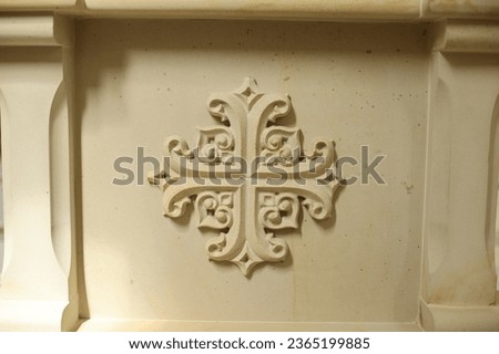 An ornate cross on the wall of a Catholic church, crafted from clay, adds to the spiritual ambiance.