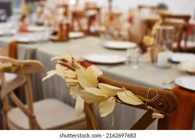 Ornate Of Dry Leaves On Wooden Chair Back In Restaurant