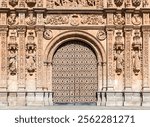 The ornate facade of a historic building in Salamanca features intricate carvings and a grand archway, celebrating artistry and history.