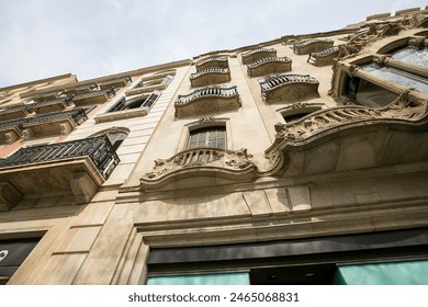 Ornate facade of a historical building in a European city, featuring intricately designed balconies and windows with detailed stone carvings and wrought iron railings. Classic European architecture - Powered by Shutterstock