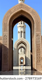 Ornate mosque arch frames repeating gateways and distant minaret, while carved details, polished courtyard floor, perfect symmetry travel destination elegance emphasize serene Islamic architecture.