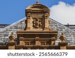 Ornate pediment with "1885" shield emblem on historic building facade, showcasing intricate stone carvings and architectural craftsmanship