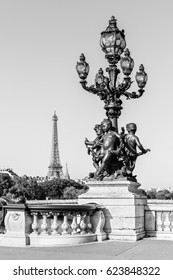 Ornate renaissance street lamp on the famous Pont Alexandre III bridge in central Paris with  Eiffel Tower in the distance in black and white. Paris, France