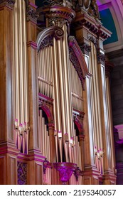 Ornate vintage pipe organ pipes with carved wooden decoration. Gold gilded sound pipes bathed in purple light. Musical instrument craftsmanship and relifgious opulent, decadence. - Shutterstock ID 2195340057