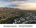 Oro Valley, Arizona: Experience a stunning aerial sunset view showcasing the majestic mountains bathed in warm hues of orange and pink.