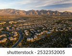 Oro Valley, Arizona: Experience a stunning aerial sunset view showcasing the majestic mountains bathed in warm hues of orange and pink.