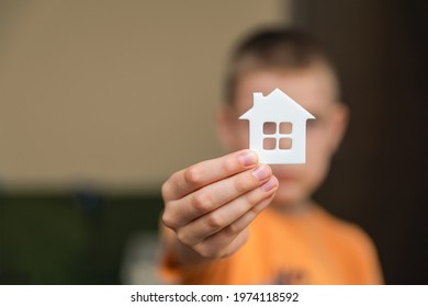 Orphanage, Children In The Orphanage. The Child Is Holding A Small House-shaped Figurine, Close-up. Adoption Concept. Banner, Place For Text