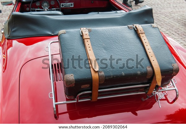 OrtEsens, Germany -\
September 19, 2021: Rear view of a Karman Ghia convertible with\
strapped black suitcase on a chrome-plated luggage rack at a\
classic car show. 