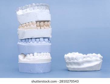 Orthodontic concept: vertical stack of dental gypsum molds with invisible braces next to a separate plaster jaw model.