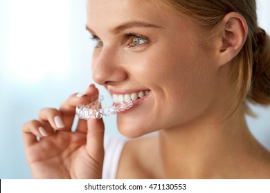 Orthodontics. Closeup Of Beautiful Happy Smiling Woman With White Smile, Straight Teeth Holding Whitening Tray, Invisible Braces, Teeth Trainer. Dental Treatment, Health Concept. High Resolution Image