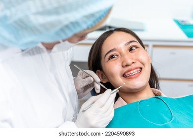 Orthodontist doctor examine tooth to woman patient at dental clinic. Attractive young girl with braces lying on dental chair, getting dental treatment from dentist during procedure service in hospital - Powered by Shutterstock