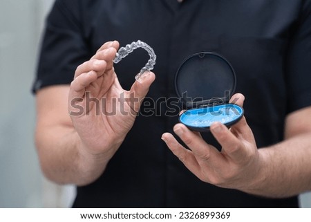 Orthodontist taking out clear aligners for teeth correction of open case in stomatology clinic doctor in black uniform showing alternative braces in medical center closeup