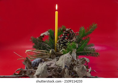 Orthodox Christmas decoration, burning candle in basket with pine tree, oak tree leaves, pine cone on red background - Powered by Shutterstock