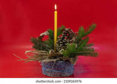 Orthodox Christmas decoration, burning candle in basket with pine tree, oak tree leaves, pine cone on red background - Powered by Shutterstock