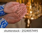 Orthodox cross in the hands of woman mother during baptism, concept hope, close-up