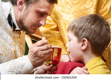 Orthodox Euharist Ceremony. Priest Makes Child Communion With Bowl In Church