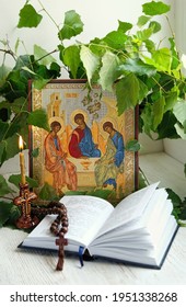 orthodox icon of Holy Trinity, candle, rosary beads, birch leaves, bible books. Holy Trinity Sunday. festive traditional composition for Pentecost day. concept of faith, God, orthodox Church, religion