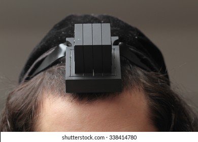 An orthodox Jew putting tefillin on his head