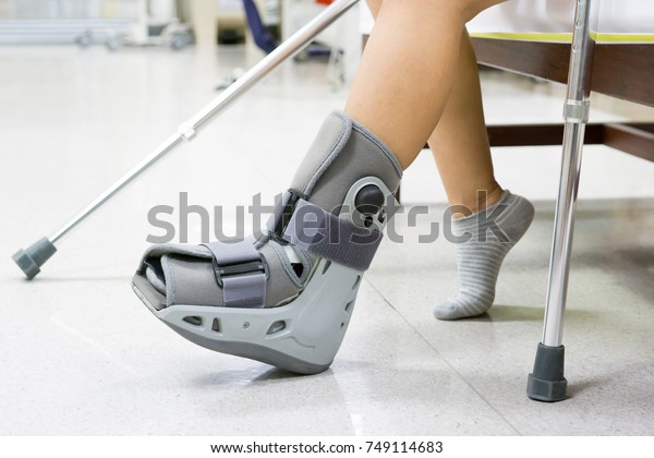 Orthopaedic Boot and crutch\
to a Patient.