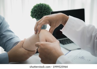 Orthopaedic Doctor Doing Physical Examination Patient With Wrist Pain At The Clinic. Physical Therapist Checks The Patient Wrist By Pressing The Wrist Bone.