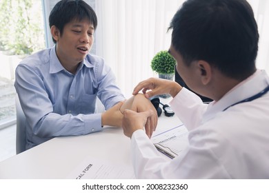 Orthopaedic Doctor Doing Physical Examination Patient With Wrist Pain At The Clinic. Physical Therapist Checks The Patient Wrist By Pressing The Wrist Bone.