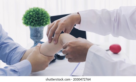 Orthopaedic Doctor Doing Physical Examination Patient With Wrist Pain At The Clinic. Physical Therapist Checks The Patient Wrist By Pressing The Wrist Bone.