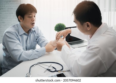 Orthopaedic Doctor Doing Physical Examination Patient With Wrist Pain At The Clinic. Physical Therapist Checks The Patient Wrist By Pressing The Wrist Bone.