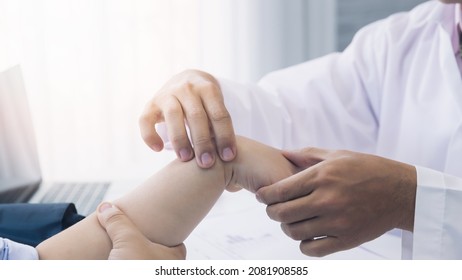 Orthopaedic Doctor Doing Physical Examination Patient With Wrist Pain At The Clinic. Physical Therapist Checks The Patient Wrist By Pressing The Wrist Bone.