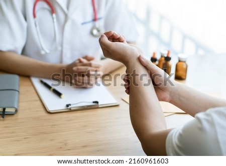 Orthopaedic doctor doing physical examination in the patient with wrist pain at the clinic. Pain from tendonitis and sport injury. Medical and physical therapy concept.