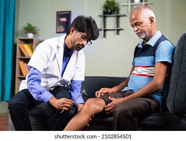 Orthopaedic Doctor Or Physician Checking Knee Joint Pain Of Senior Man By Using Knee Hammer At Home - Concept Of Arthritis, Healthcare And Injury Treatment.