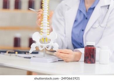 An orthopedic doctor shows a spinal model to a patient in a human spinal hospital. Diseases and disorders of the spinal cord, back pain, lumbar pain, orthopedic surgery, chiropractic, office syndrome